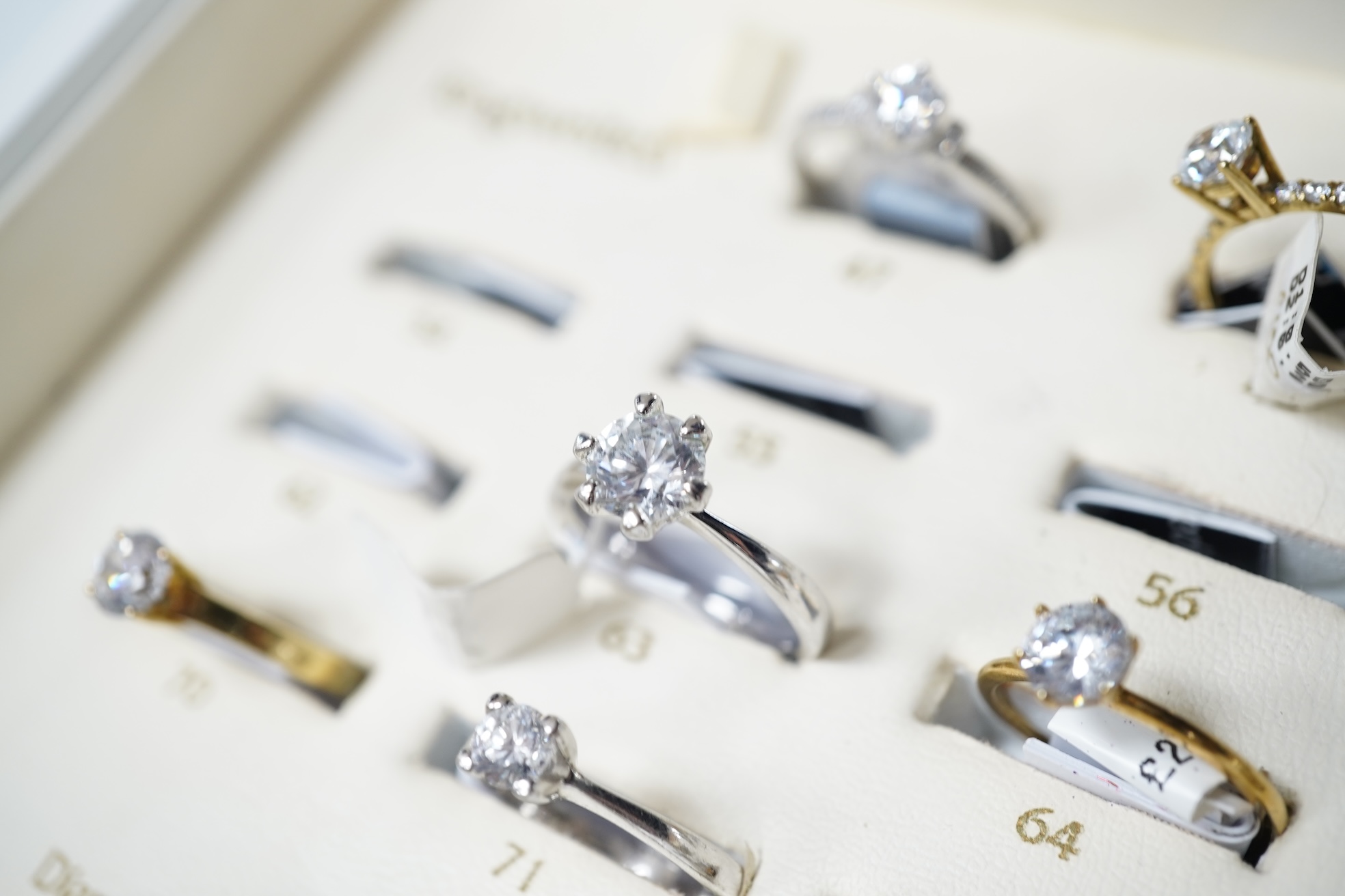 A collection of 22 simulant diamond rings, variously mounted in silver and base metal, one in platinum, British hallmarks, together with a ring display unit